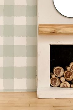 a pile of logs sitting in front of a wall mounted fire place with a clock on it