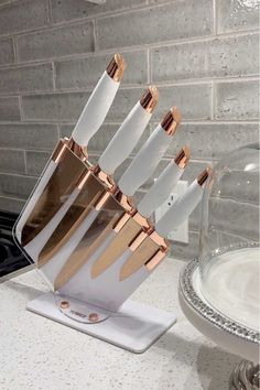 a set of knives in a holder on a counter top next to a glass dish