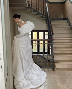 a woman in a wedding dress standing on the stairs