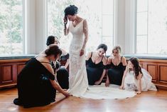 a bride and her bridal party sitting on the floor in front of large windows