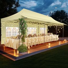 a large tent set up with tables and chairs for an outdoor dinner party at night