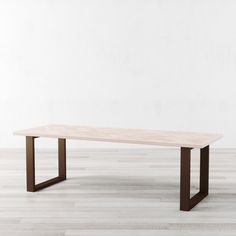 a wooden table sitting on top of a hard wood floor next to a white wall