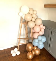 a ladder with balloons on top of it in a room next to a counter and cabinets