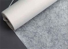 a roll of white paper on top of a gray surface with an image of a flower pattern