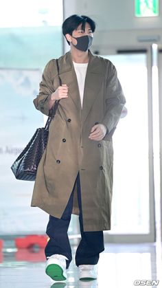 a man in a trench coat is walking down the runway with his hand on his hip