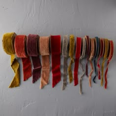 multicolored scarves hanging on the wall in a row with fringes attached to them