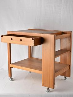 a wooden table with two drawers on wheels