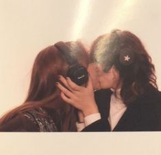 two people kissing each other while holding a camera