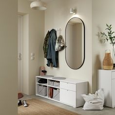 a room with a mirror, coat rack and white cabinets