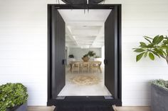 an open door leading to a dining room and kitchen area with potted plants on either side