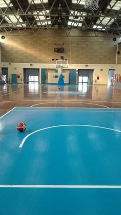 an indoor basketball court with a ball on the floor