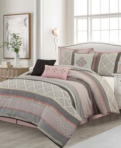 a bed in a bedroom with pink and gray comforter set on top of it