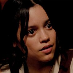 a close up of a person wearing a necklace and looking at the camera with an intense look on her face