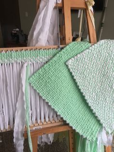 a crocheted baby blanket sitting on top of a wooden chair next to a ladder