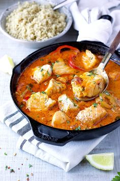 a skillet filled with chicken and vegetables next to rice