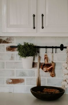 a kitchen with white cabinets and wooden utensils hanging on the wall above a frying pan