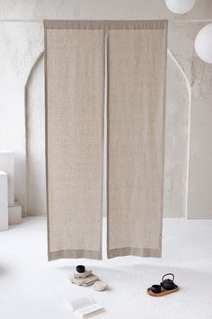 a pair of beige curtains sitting on top of a white floor next to two pairs of shoes