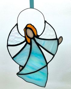 a stained glass angel ornament hanging from a blue ribbon on a white background