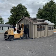 a forklift is parked in front of a storage shed with a man standing on it