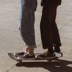 two people standing on top of a skateboard