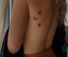 a woman's back with three butterflies tattoo on her left shoulder and right breast