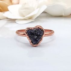 a ring with a black druzby stone in the middle and a white rose behind it