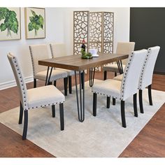 a dining room table with four chairs and a white rug on the floor in front of it