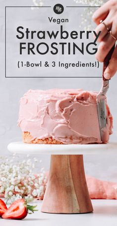 a person cutting into a strawberry frosting cake on top of a white plate with strawberries