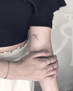 a woman's left arm with a small tattoo on the middle part of her right arm