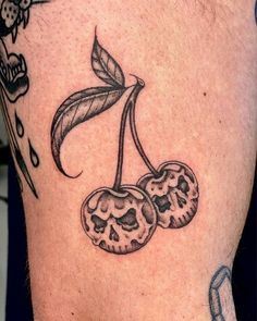 two cherries with leaves on the side of a man's leg, one is black and white