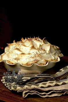 a pie sitting on top of a wooden table next to a fork and napkins