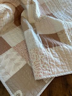 an unmade quilt on top of a wooden floor