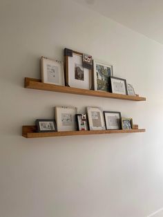 three wooden shelves with pictures on them against a white wall in a living room area