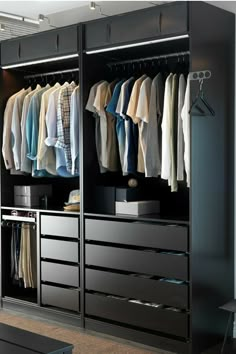 an open closet with clothes hanging on the wall and drawers in front of it,