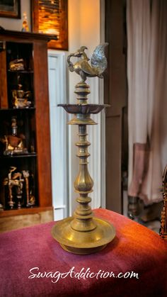 an antique brass candle holder on top of a red table cloth in a living room