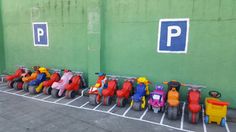 toy cars lined up in front of a green wall with parking spaces painted on it