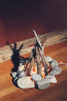 there is a fire pit made out of rocks and wood on the floor next to a wall