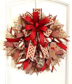 a red and white christmas wreath hanging on a door