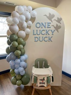 a baby's high chair next to a balloon arch that says one lucky duck