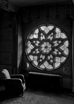 a chair sitting in front of a large stained glass window