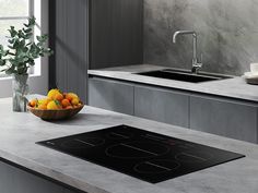 a bowl of fruit sitting on top of a counter next to a sink and stove