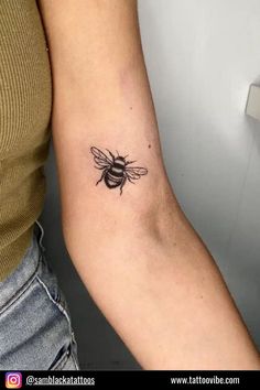 a woman's arm with a small tattoo of a bee on the back of her arm