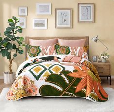 a bed covered in lots of colorful pillows and blankets next to a potted plant