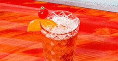 an orange and white drink on a wooden table with a cherry in the top corner