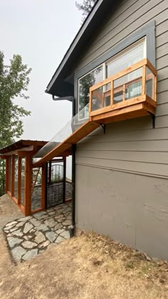 a house with a wooden deck on top of it's roof next to a stone walkway