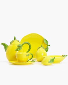 a yellow tea set with lemons on the side and green leaves in the middle