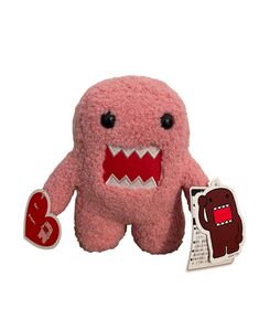 a pink stuffed animal with large teeth and big eyes holding a heart shaped sticker