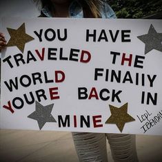 a woman holding a sign that says you have traveled the world finally you're back in mine