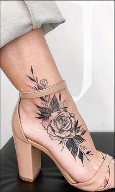 a woman's foot with a butterfly and rose tattoo on her left side ankle