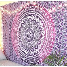 a large purple and white tapestry hanging on the side of a wall next to a plant